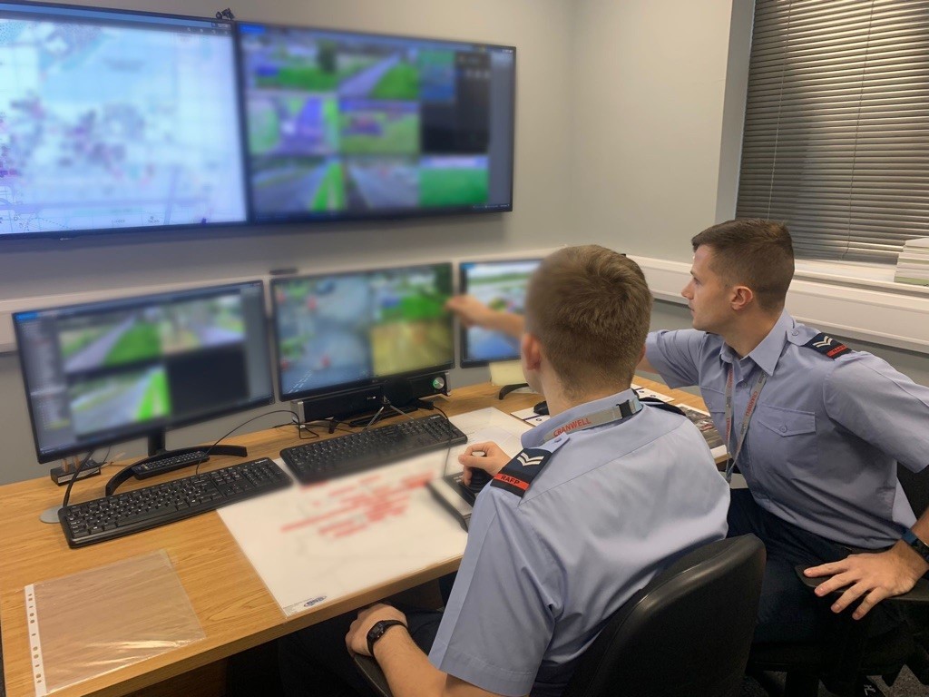 Image shows RAF aviators pointing to computer screens at desk.